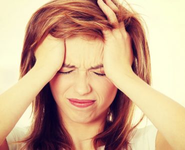 A woman holding her head in pain representing a migraine