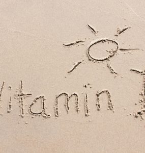 Vitamin D and a sunshine written into the sand on beach
