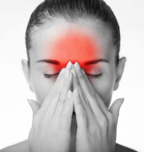 Woman in black and white with red highlighting over forehead to denote headache