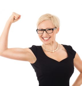Woman wearing black dress with arm raised in triumph at her weight loss