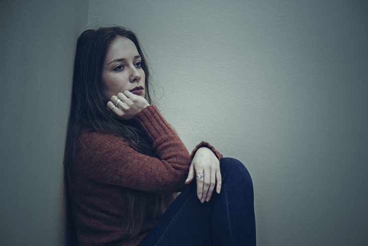 Woman sitting on floor looking sad demonstrating low mood