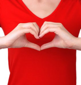Torso shot of woman in red t-shirt making a heart symbol with her hands in front of her chest