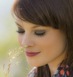 Close up of woman smelling wild flowers to show hay fever