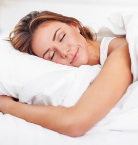 Woman hugging pillow whilst sleeping in bed