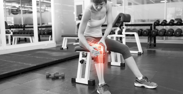 Woman at the gym sitting on a bench with joint pain indicated by a red glow around her knee