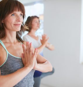 Woman doing yoga standing with hands in prayer position