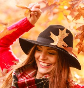Close up of happy woman in autumn with falling leaves