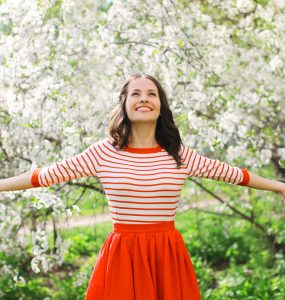 Happy young woman in front of a blossom tree to show spring season