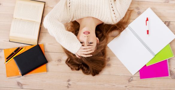 Woman lying on floor surrounded by work representing stress