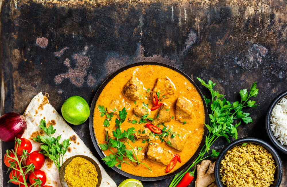 A curry surrounded by curry ingredients including ginger