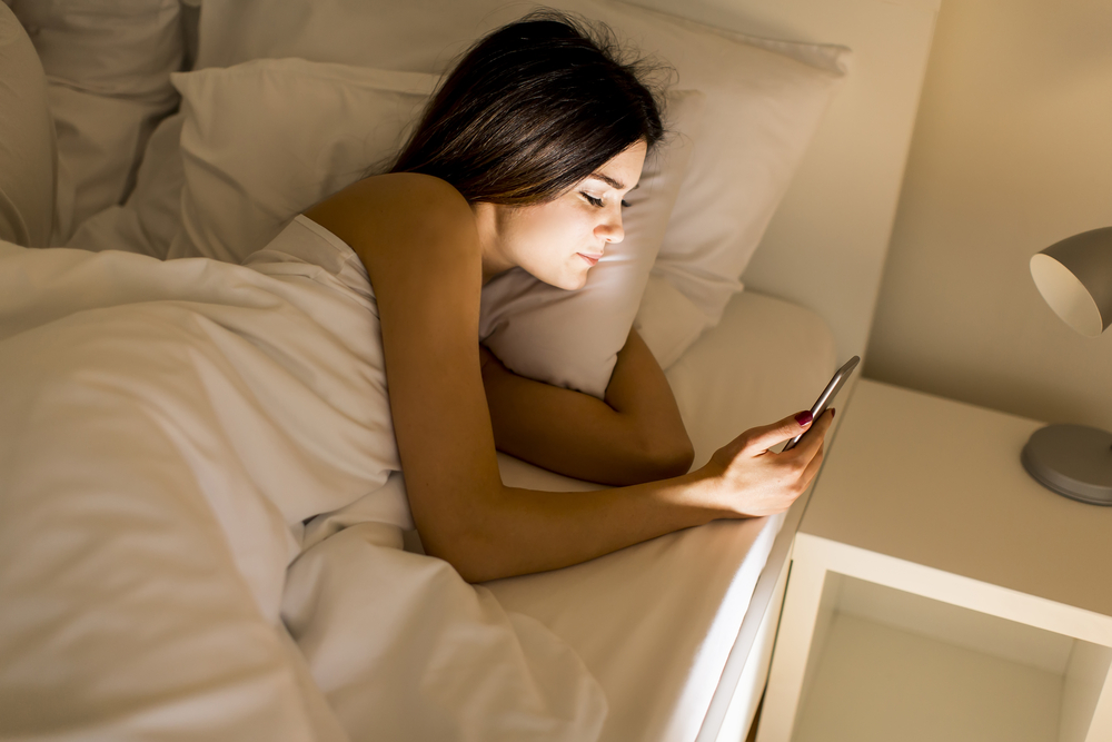 Woman in bed looking at mobile phone
