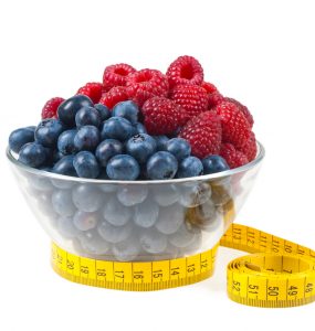 A bowl of fruit with a measuring tape around it to represent weight management