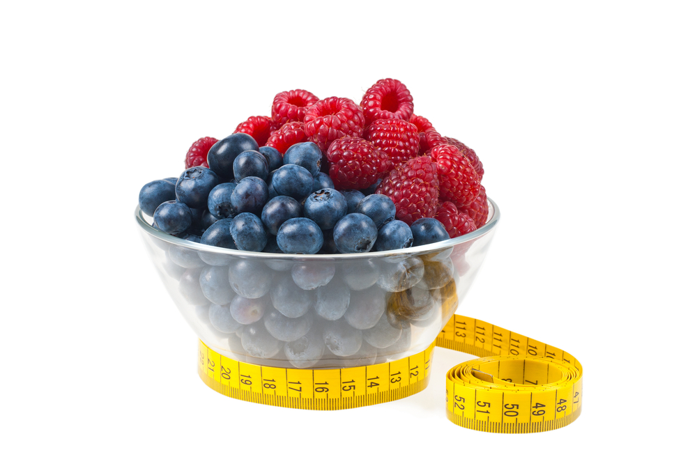 A bowl of fruit with a measuring tape around it to represent weight management