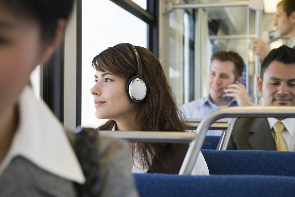Close up of woman wearing headphones commuting to work on a bus