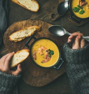 Close up of woman in cosy jumper eating soup