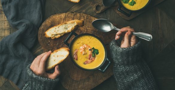 Close up of woman in cosy jumper eating soup