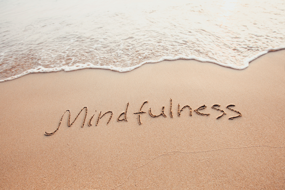 The word mindfullness written in sand on a beach