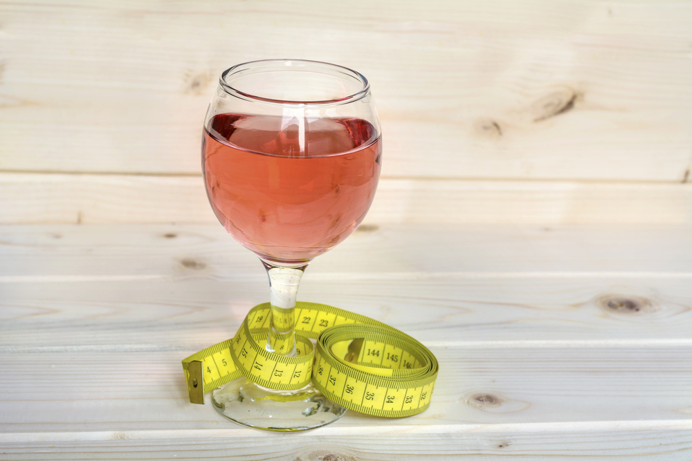 Glass of low alcohol wine and a tape measure to represent weight management