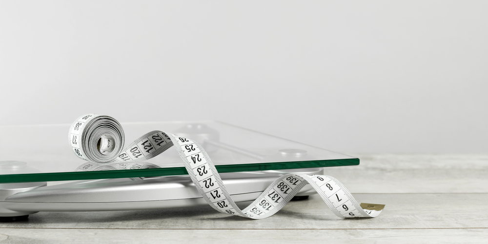 A measuring tape and scales to represent weight management